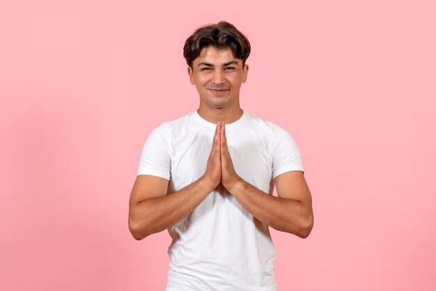 Vooraanzicht jonge man glimlachend in wit t-shirt op roze achtergrond