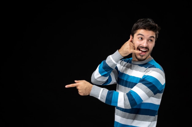 Vooraanzicht jonge man in blauw gestreepte trui op zwarte muur fotomodel duisternis menselijke kleuren