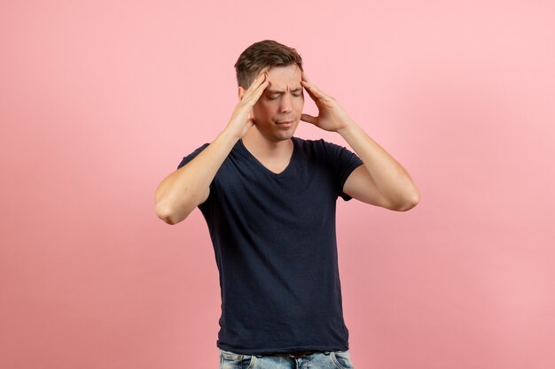 Vooraanzicht jonge man in donkerblauw shirt met lichte hoofdpijn op roze achtergrond mannelijk menselijk model kleur emotie man