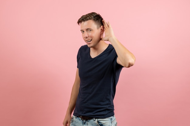 Vooraanzicht jonge man in donkerblauw shirt nauw luisteren op roze achtergrond mannelijke emotie menselijke model kleur man
