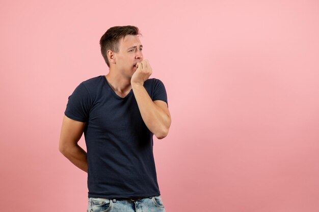 Vooraanzicht jonge man in donkerblauw shirt poseren op roze bureau