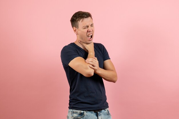 Vooraanzicht jonge man in donkerblauw shirt zichzelf stikken op roze achtergrond emotie mannelijk menselijk model kleur man