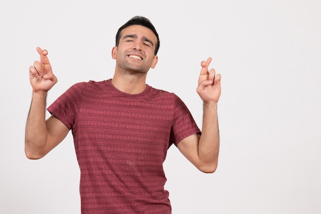 Vooraanzicht jonge man in donkerrood t-shirt die zijn vingers kruist op witte achtergrond