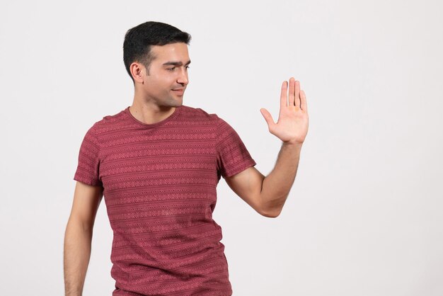 Vooraanzicht jonge man in donkerrood t-shirt staande op witte achtergrond