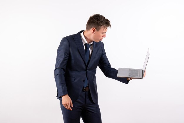 Vooraanzicht jonge man in elegant klassiek pak met laptop op witte achtergrond