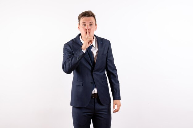 Vooraanzicht jonge man in elegant klassiek pak vragen om stil te zijn op een witte achtergrond