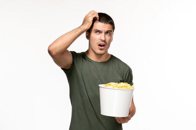 Vooraanzicht jonge man in groen t-shirt aardappel cips houden en denken aan witte muur eenzame film film bioscoop