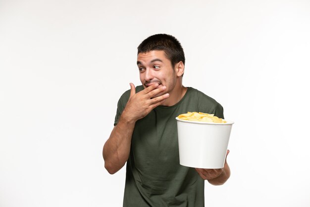 Vooraanzicht jonge man in groen t-shirt aardappel cips houden en lachen op witte muur eenzame film film bioscoop persoon