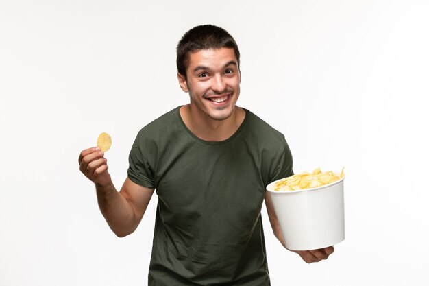 Vooraanzicht jonge man in groen t-shirt met aardappel cips en eten op wit bureau persoon eenzame film film bioscoop