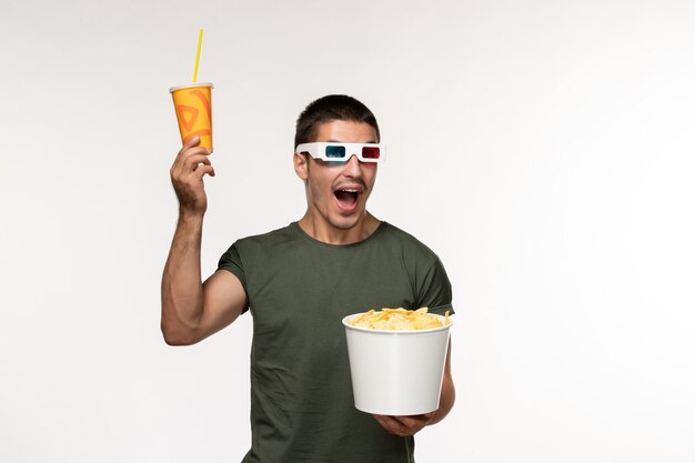 Vooraanzicht jonge man in groen t-shirt met aardappel cips en frisdrank in d zonnebril op witte muur mannelijke eenzame film