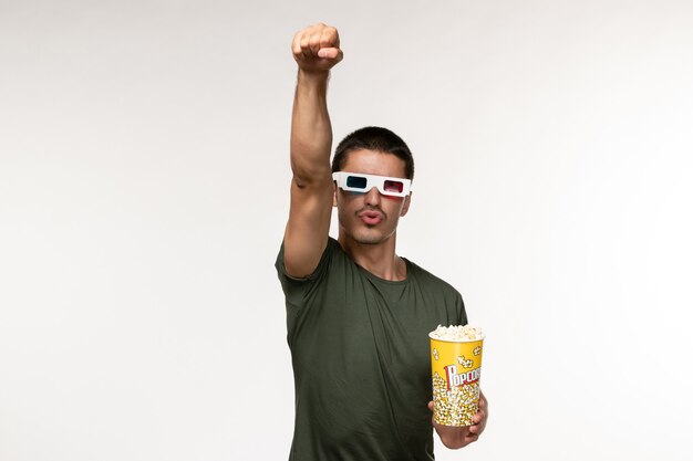 Vooraanzicht jonge man in groen t-shirt popcorn houden d zonnebril dragen en buigen op witte muur film eenzame bioscoop