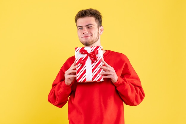 Vooraanzicht jonge man in rood shirt met kerstcadeau