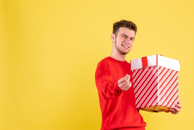 Vooraanzicht jonge man in rood shirt met kerstcadeau