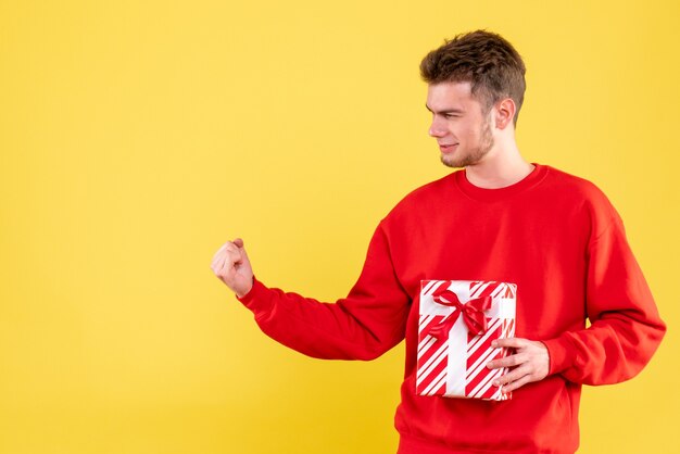 Vooraanzicht jonge man in rood shirt met kerstcadeau