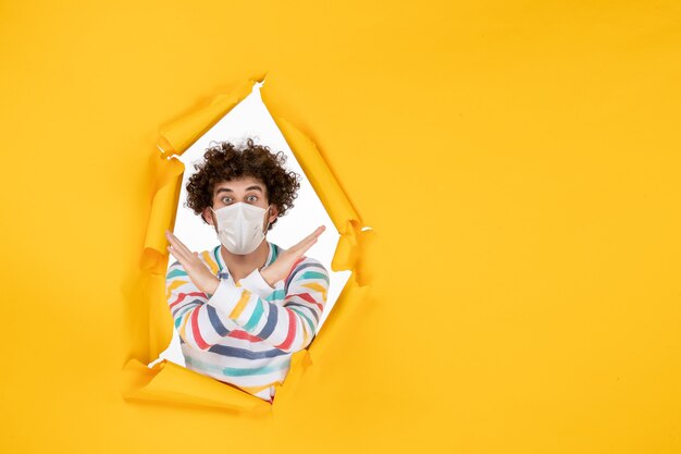 Vooraanzicht jonge man in steriel masker op gele gezondheidskleurenfoto covid-virus mens