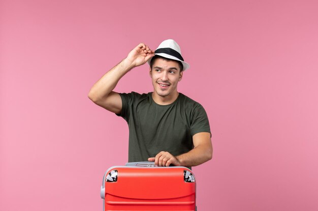 Vooraanzicht jonge man in vakantie met zijn rode tas op de roze ruimte