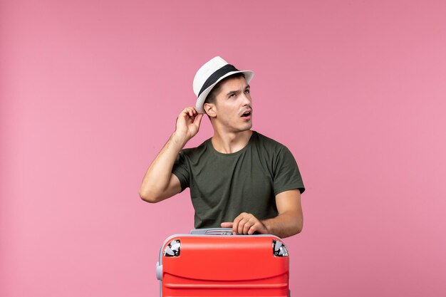 Vooraanzicht jonge man in vakantie met zijn rode tas op roze bureau