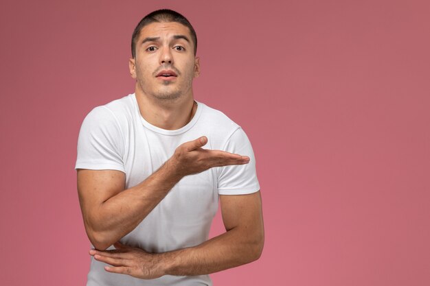 Vooraanzicht jonge man in wit overhemd met opgeheven hand op de roze achtergrond