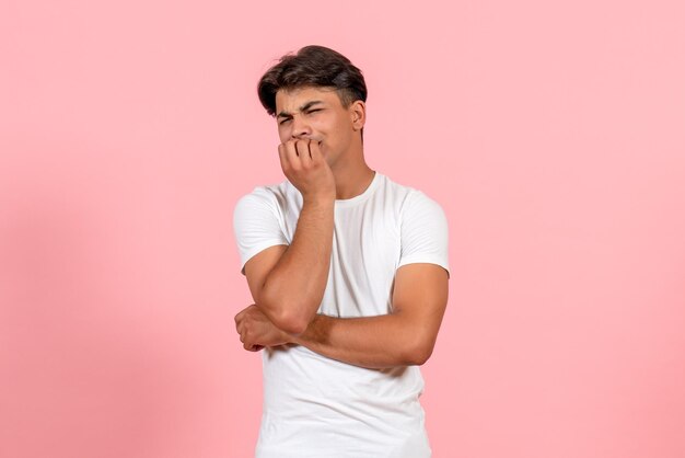 Vooraanzicht jonge man in wit t-shirt zenuwachtig op roze achtergrond
