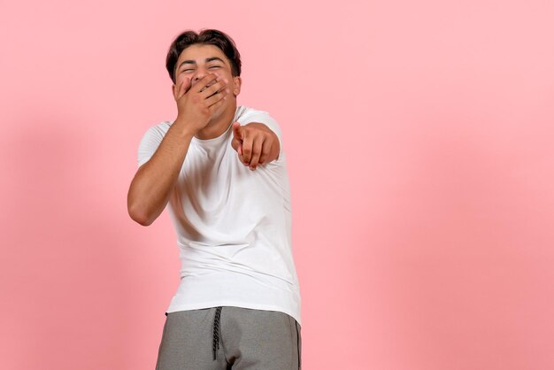 Vooraanzicht jonge man lachen in wit t-shirt op roze achtergrond