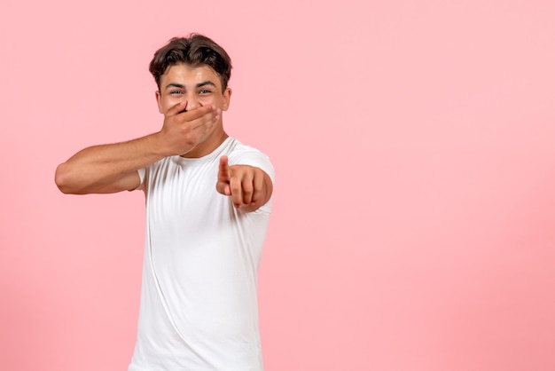 Vooraanzicht jonge man lachen in wit t-shirt op roze achtergrond