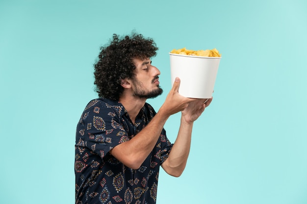 Vooraanzicht jonge man met aardappel cips op lichtblauwe muur bioscoop films film theater man