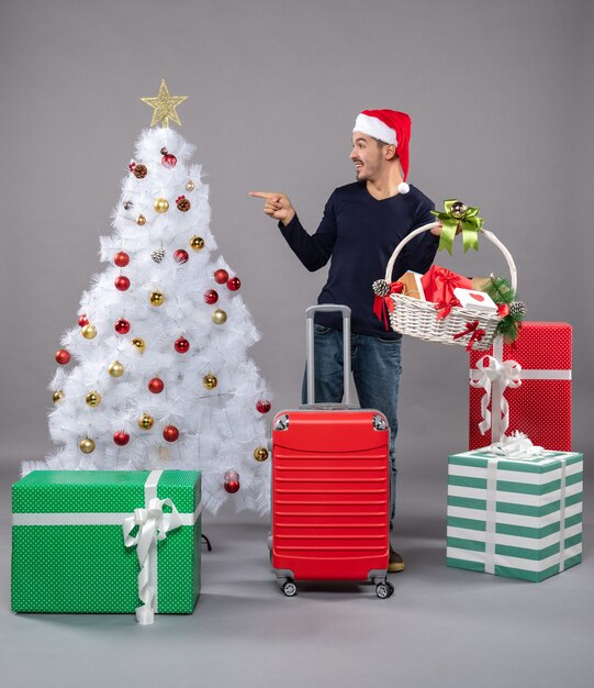 Vooraanzicht jonge man met cadeaumand met witte kerstboom op grijs geïsoleerd