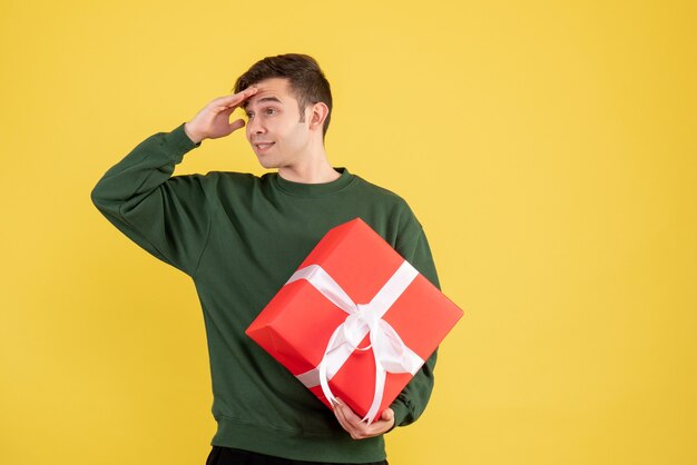 Vooraanzicht jonge man met groene trui iets op geel te kijken