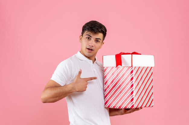 Vooraanzicht jonge man met grote kerstcadeautjes op roze achtergrond