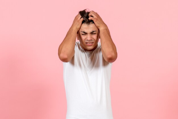 Vooraanzicht jonge man met hoofdpijn op roze achtergrond mannelijke kleur model emotie