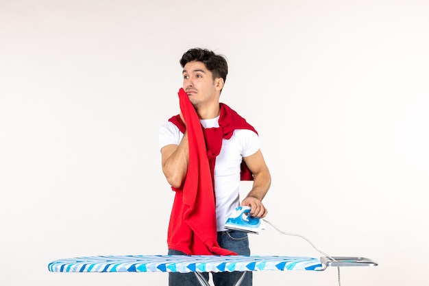 Vooraanzicht jonge man met ijzer en rode handdoek op witte achtergrond thuis kleur werk man huishoudelijk werk schone emotie
