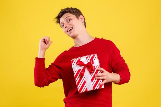 Vooraanzicht jonge man met kerst aanwezig op gele achtergrond