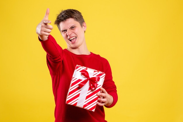 Vooraanzicht jonge man met kerst aanwezig op gele achtergrond