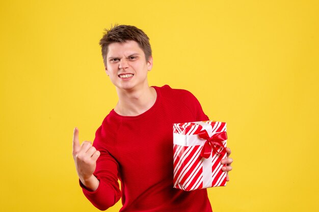 Vooraanzicht jonge man met kerst aanwezig op gele achtergrond