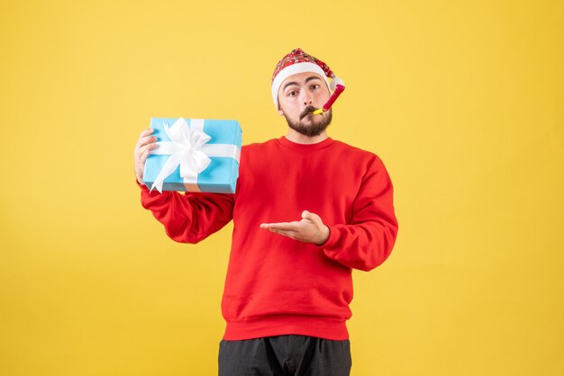 Vooraanzicht jonge man met kerst aanwezig op gele achtergrond