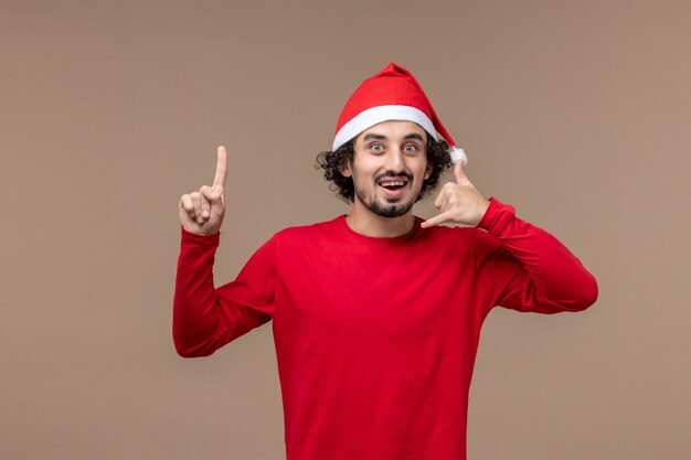 Vooraanzicht jonge man met kerst cape op de bruine achtergrond emotie vakantie kerst