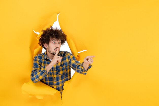 Gratis foto vooraanzicht jonge man met krullend haar op gele gescheurde achtergrond
