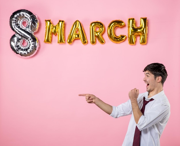 Vooraanzicht jonge man met maart decoratie op roze achtergrond huwelijksfeest man vrouwelijke vrouwen dag aanwezig kleur