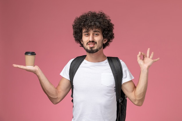 Gratis foto vooraanzicht jonge man met papieren koffiekopje in zijn hand en ok gebaar tonen