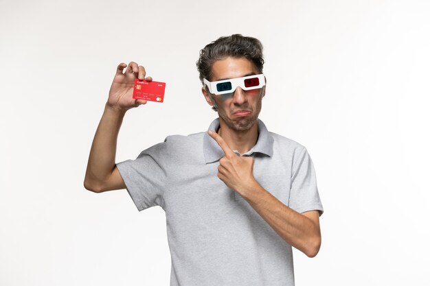 Vooraanzicht jonge man met rode bankkaart in d zonnebril op wit oppervlak