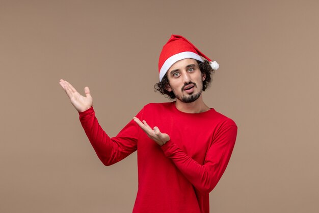 Vooraanzicht jonge man met rode kerst cape op bruine achtergrond emotie kerstvakantie