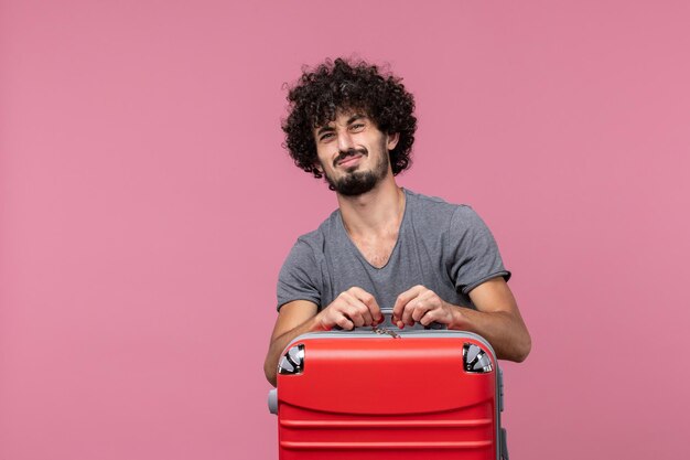 Vooraanzicht jonge man met rode tas die zich voorbereidt op een reis op de roze ruimte