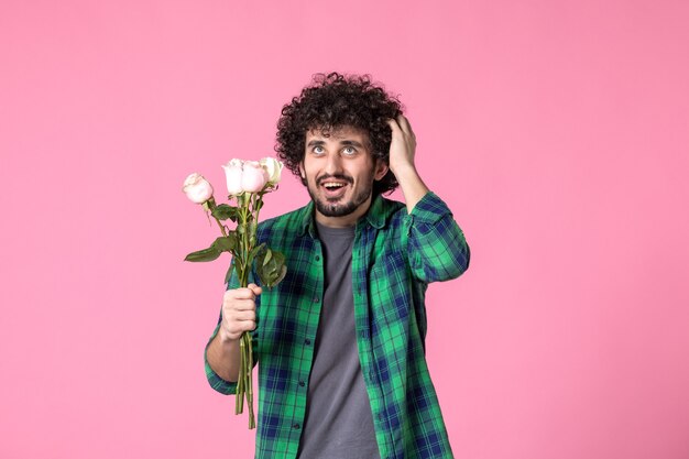 Vooraanzicht jonge man met roze rozen op roze kleur