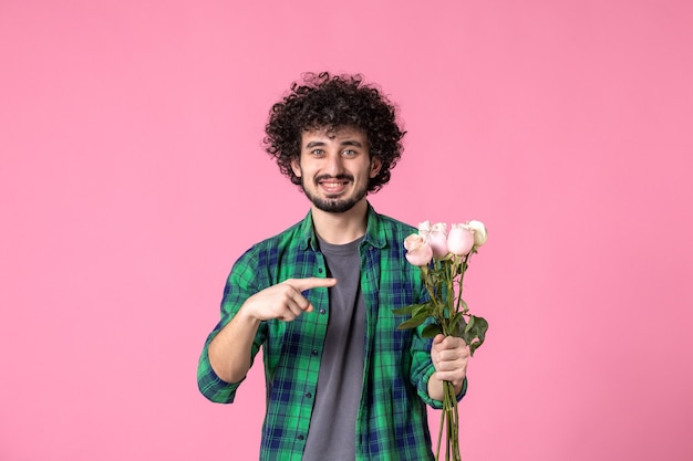 Vooraanzicht jonge man met roze rozen op roze kleuren