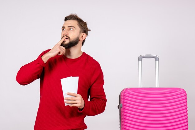 Vooraanzicht jonge man met roze tas en kaartjes houden op witte muur reis kleur vakantie vlucht reis zomertoerist