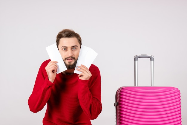 Vooraanzicht jonge man met roze tas en kaartjes houden op witte muur vlucht kleur reis reis toeristische vakantie