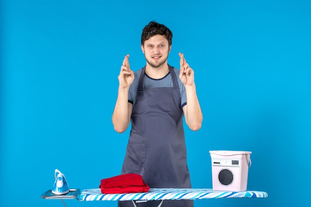 Vooraanzicht jonge man met strijkplank op het blauwe oppervlak