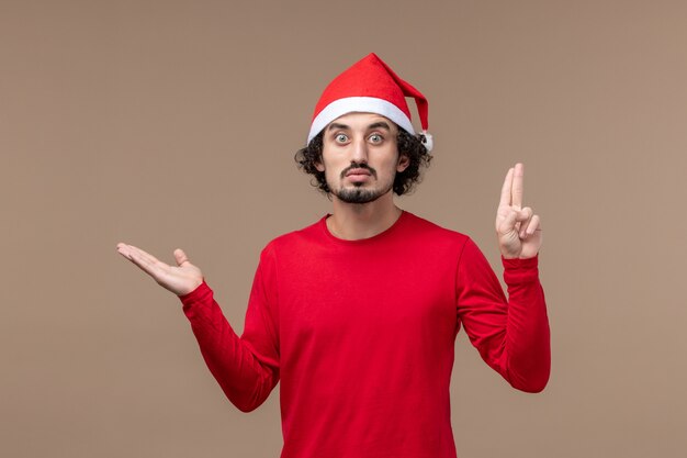 Vooraanzicht jonge man met verbaasde uitdrukking op bruin bureau vakantie emotie kerstmis
