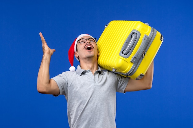Vooraanzicht jonge man met zware tas op blauwe muur vlucht vliegtuigen vakantie