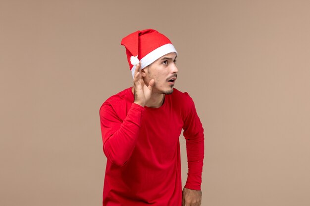 Vooraanzicht jonge man nauw luisteren op bruine achtergrond emotie kerstvakantie